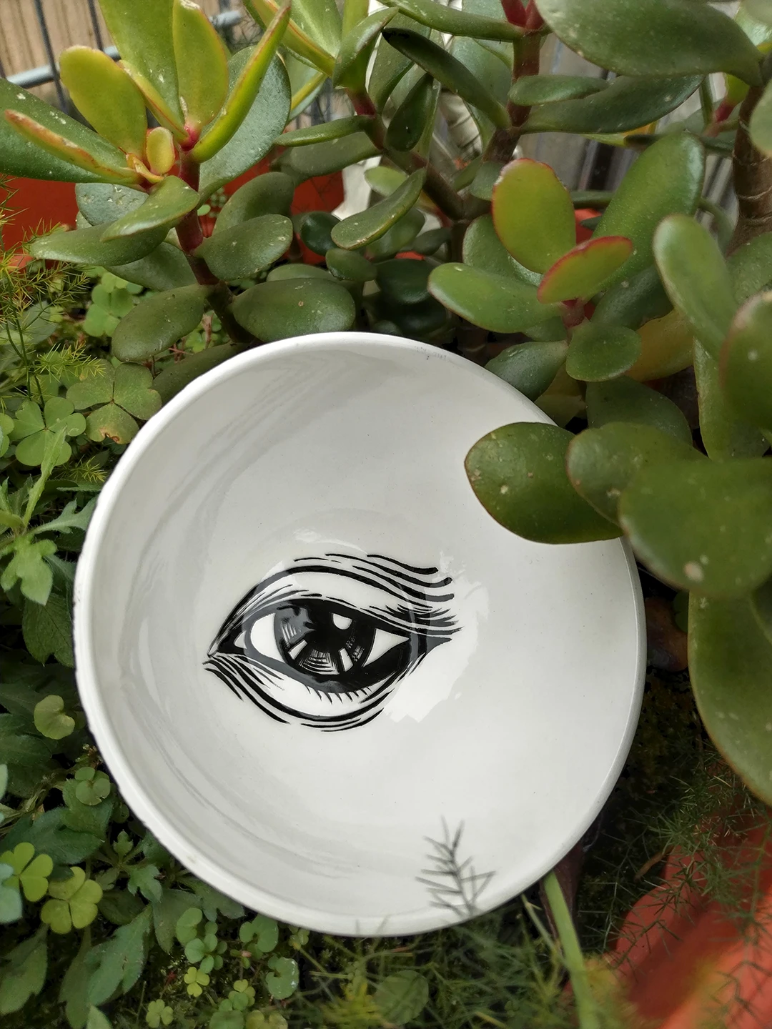 Primo piano dell'interno della piccola ciotola in ceramica. Il dettaglio si focalizza sull'occhio centrale, caratterizzato da ciglia folte e un'iride nera profonda, che richiama il tema dello sguardo pietrificante di Medusa.