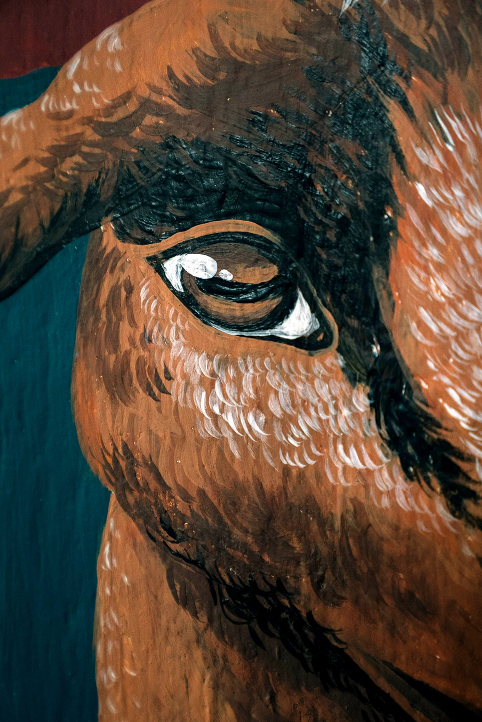 Dettaglio del murale Embrace Your Inner Child di Rosmunda che mostra in primo piano l'occhio di una capra marrone, reso con pennellate cariche di bianco e nero che ne definiscono lo sguardo e la consistenza del pelo.