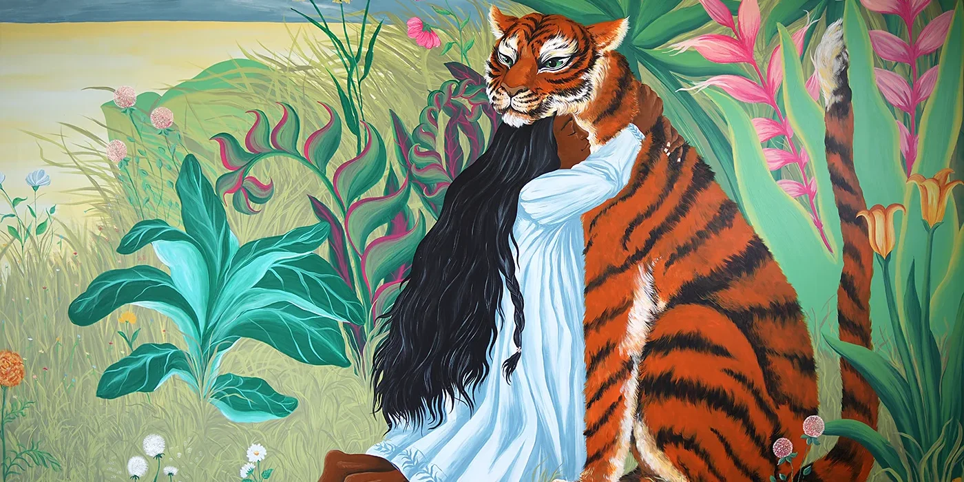 Veduta panoramica del murale Embrace Your Fears di Rosmunda che ritrae una figura femminile con lunghi capelli scuri mentre abbraccia una grande tigre, immersa in una giungla rigogliosa con piante esotiche, fiori rosa e vegetazione verde.