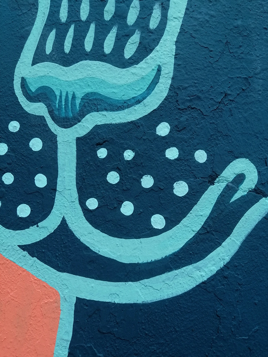 Dettaglio del murale "La Pantera" di Rosmunda che mostra un primo piano di forme organiche e stilizzate nei toni dell'azzurro e del blu scuro con motivi a puntini bianchi su una superficie muraria materica.