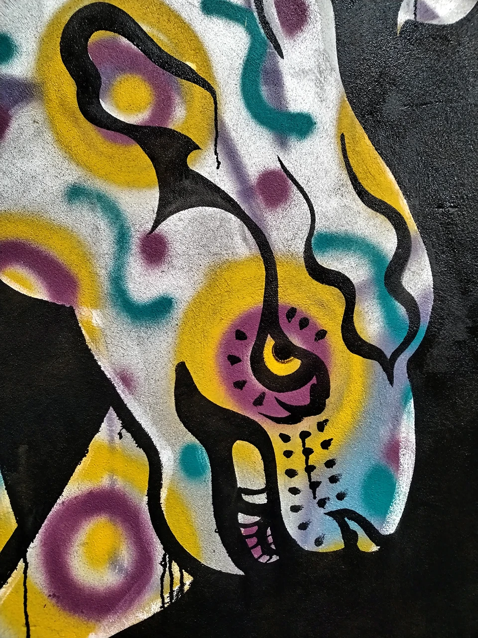 Primo piano ravvicinato della figura zoomorfa dipinta da Rosmunda, con dettagli cromatici vibranti in giallo, azzurro e viola che richiamano la natura selvaggia.